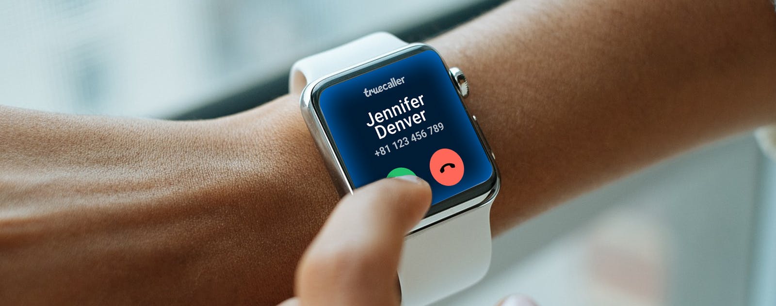 Image with a person with a smartwatch on its wrist showing an incoming call from Truecaller